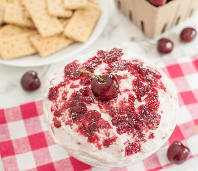 Bowl of cherry cheesecake dip and plate of graham crackers