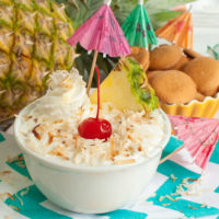 Bowl of pineapple dip with coconut topped with a cherry aka Pina Colada Dip