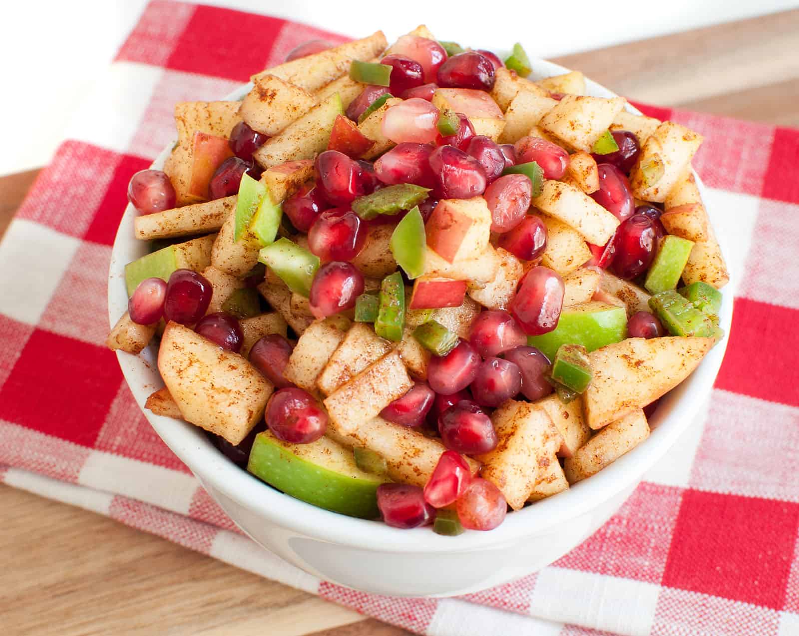 A bowl of apple salsa on a red and white checkered napkin 