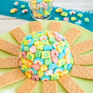 Lucky Charms Cheesecake Cheese Ball on green platter with graham crackers