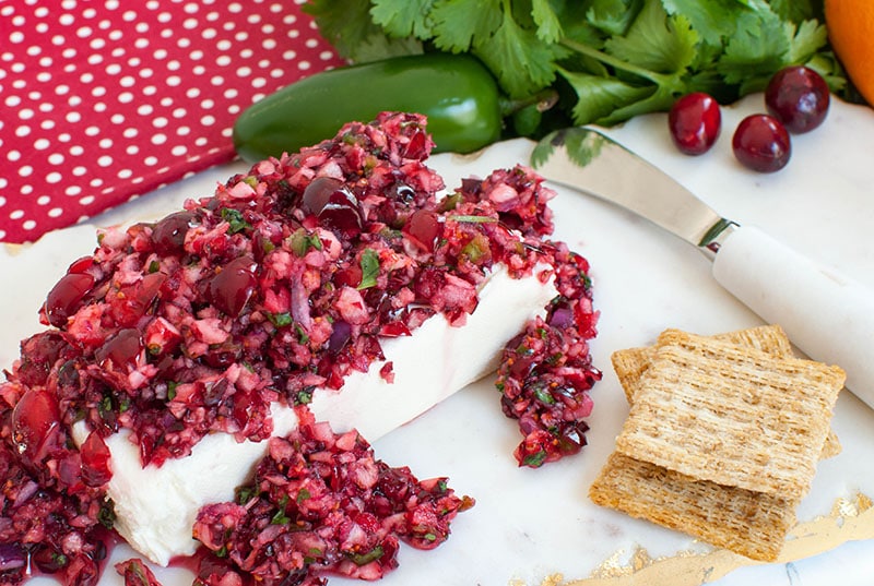 cranberry salsa over a block of cream cheese with crackers