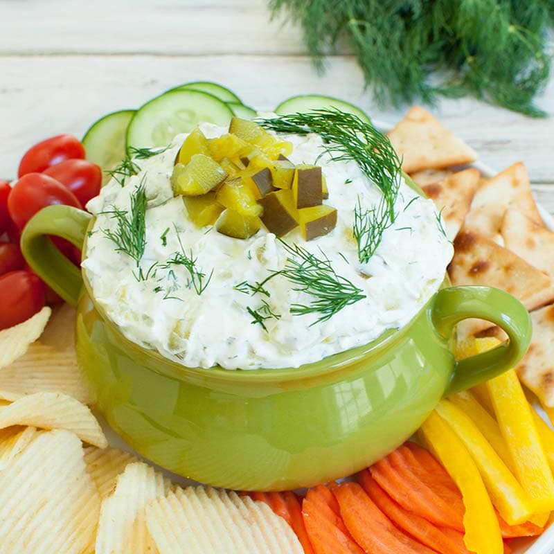 green bowl with dill pickle dip topped with chopped pickles
