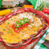 red baking dish of dip with green and white napkin