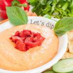 white bowl with roasted red pepper dip topped with peppers