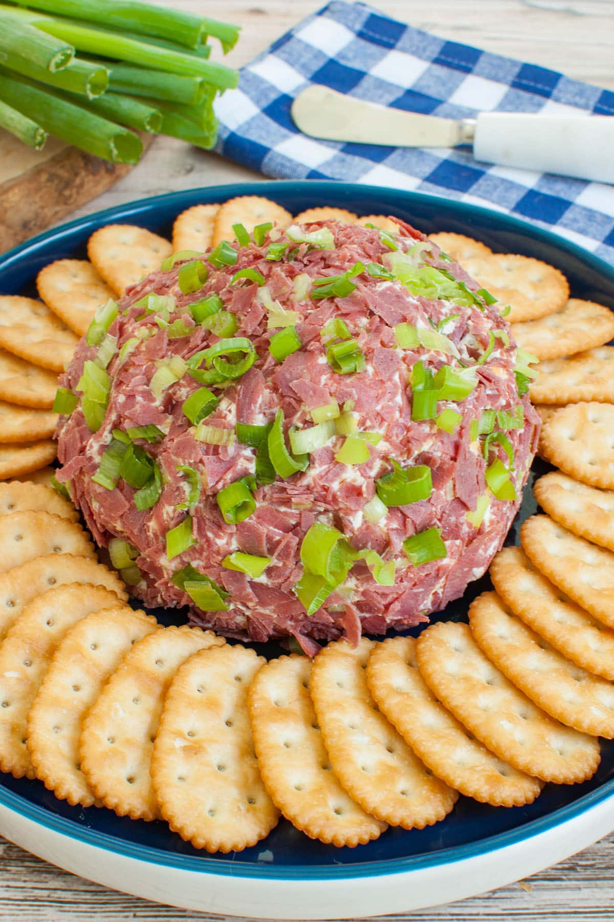chipped beef cheese ball with crackers on a blue platter with a blue and white napkin