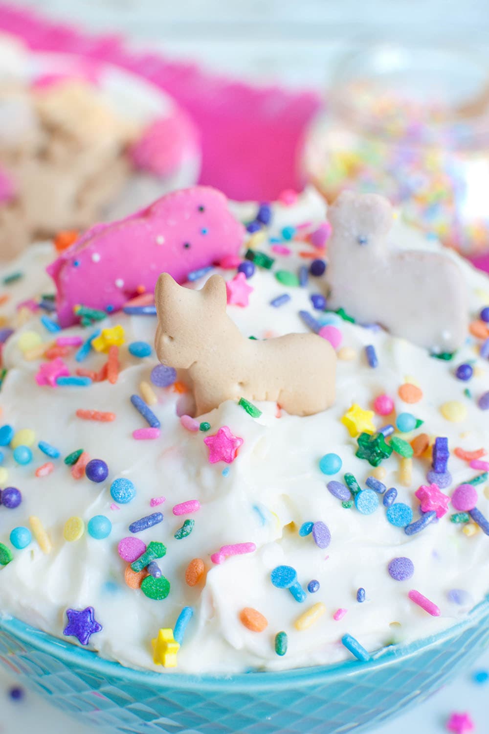 animal crackers dipped into bowl of dip with sprinkles